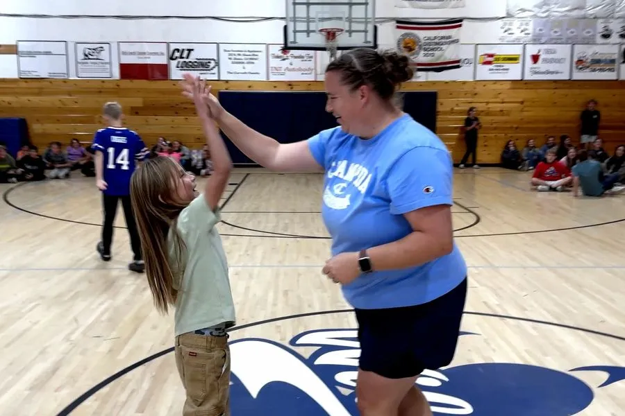 A teacher and student sharing a high-five in a school gym